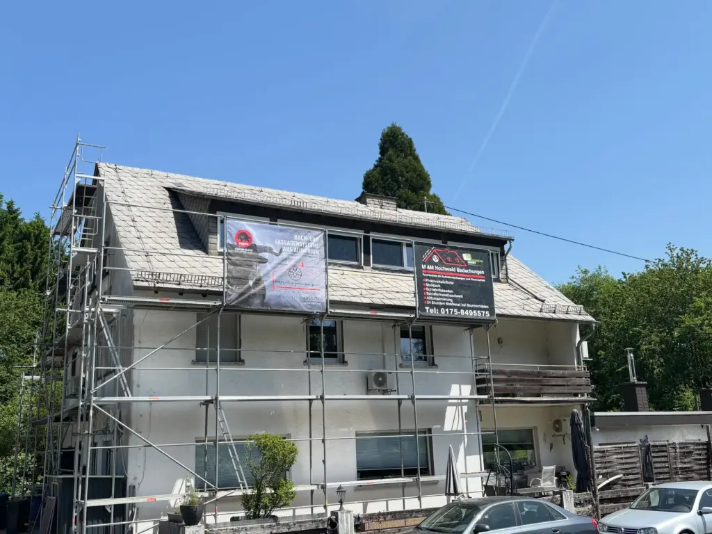 Wohnhaus mit verwittertem Schieferdach und Gerüst vor der Dachsanierung