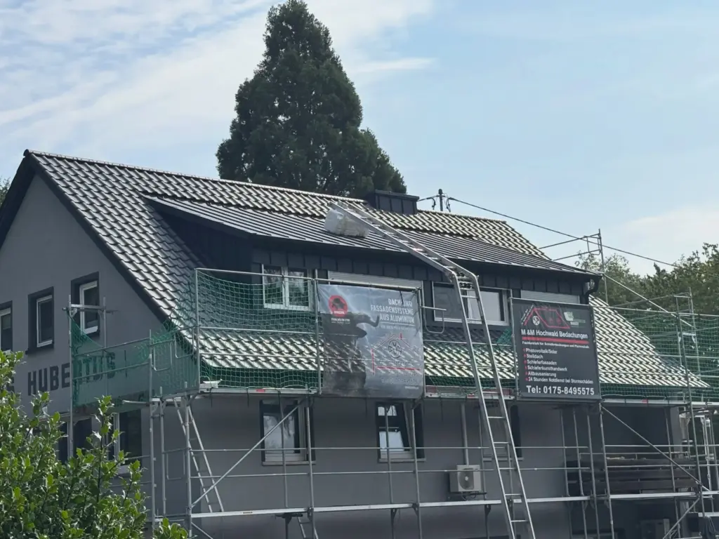 Wohnhaus nach der Dachsanierung mit neuem Ziegeldach und Gaube in Stehfalz, noch mit Gerüst