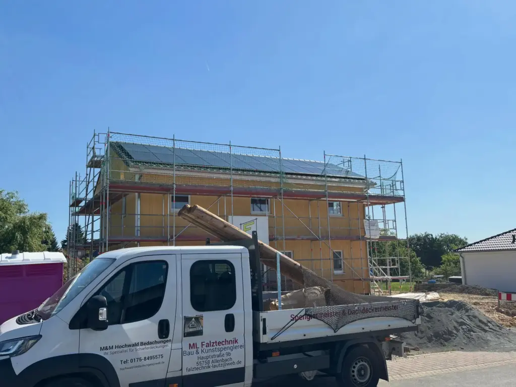 Firmenfahrzeug von ML Falztechnik vor einem Neubau mit Gerüst und Photovoltaikanlage