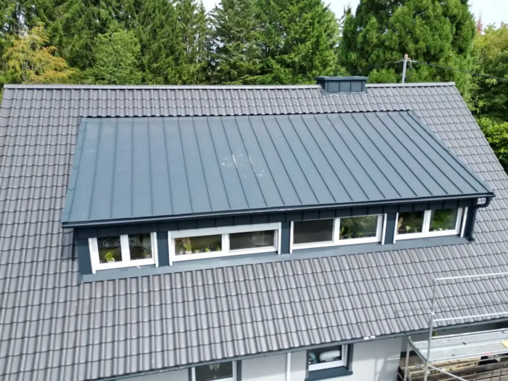Luftaufnahme einer großen Schleppgaube mit Stehfalzdeckung und Fensterband in einem Ziegeldach