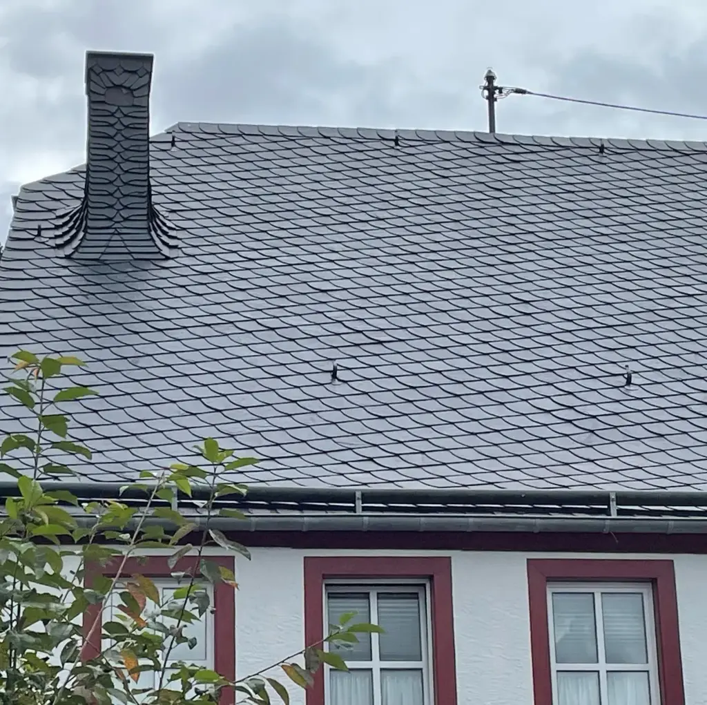 Naturschieferdach mit einem vollständig in Schiefer verkleideten Schornstein