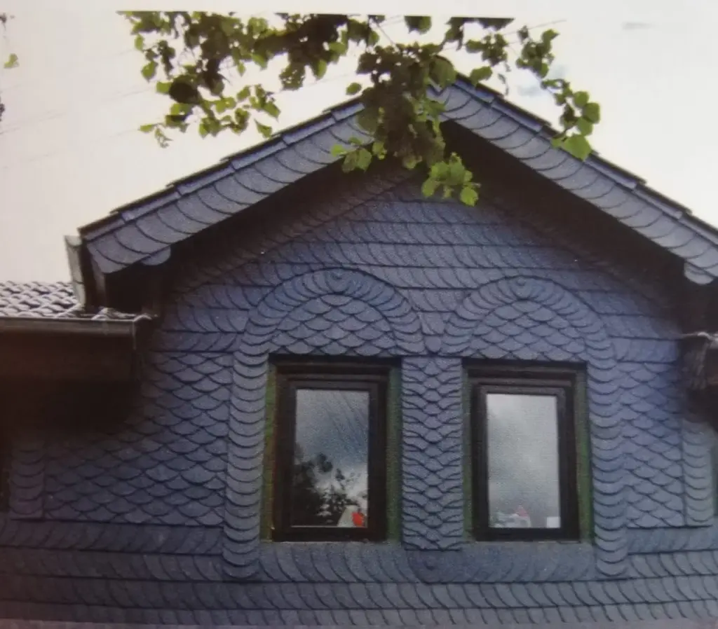 Giebelfassade in Naturschiefer mit geschwungenem Zierbogen
