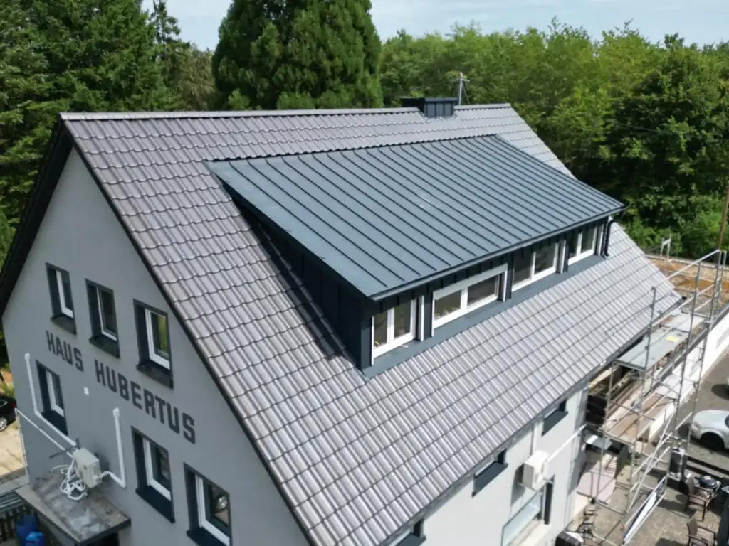 Luftaufnahme eines Wohnhauses mit neuem Ziegeldach und großer Gaube in Stehfalz