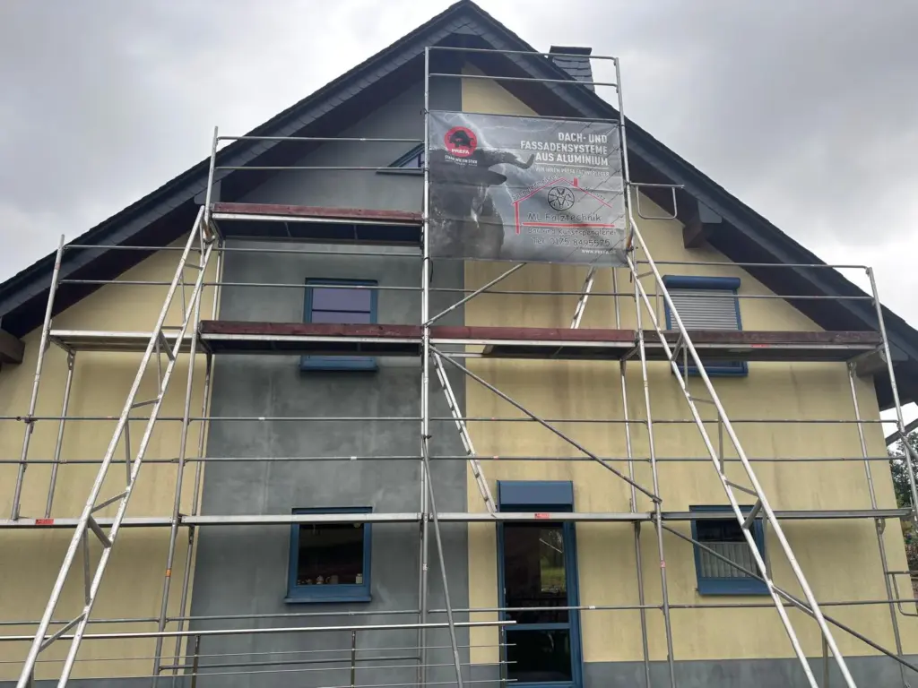 Giebelseite eines Wohnhauses in Morbach-Wenigerath mit verwittertem Putz und Gerüst vor der Fassadenbekleidung